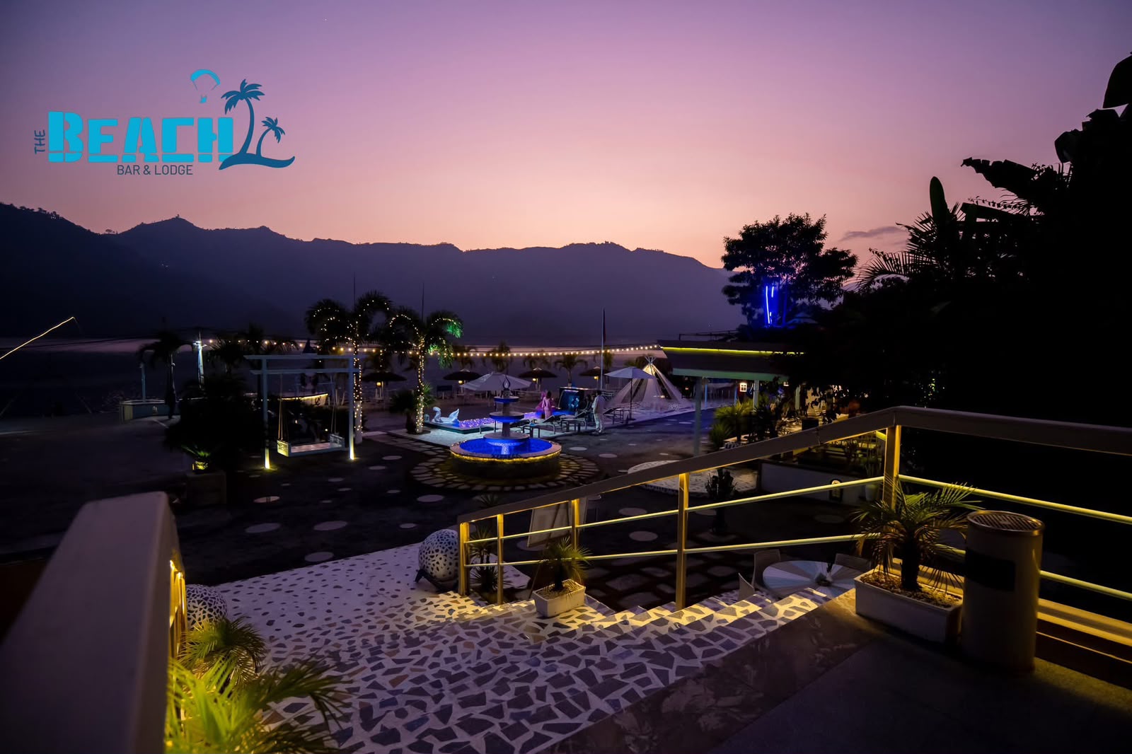 Pink sunset over The Beach, with the pool and terrace lights glowing