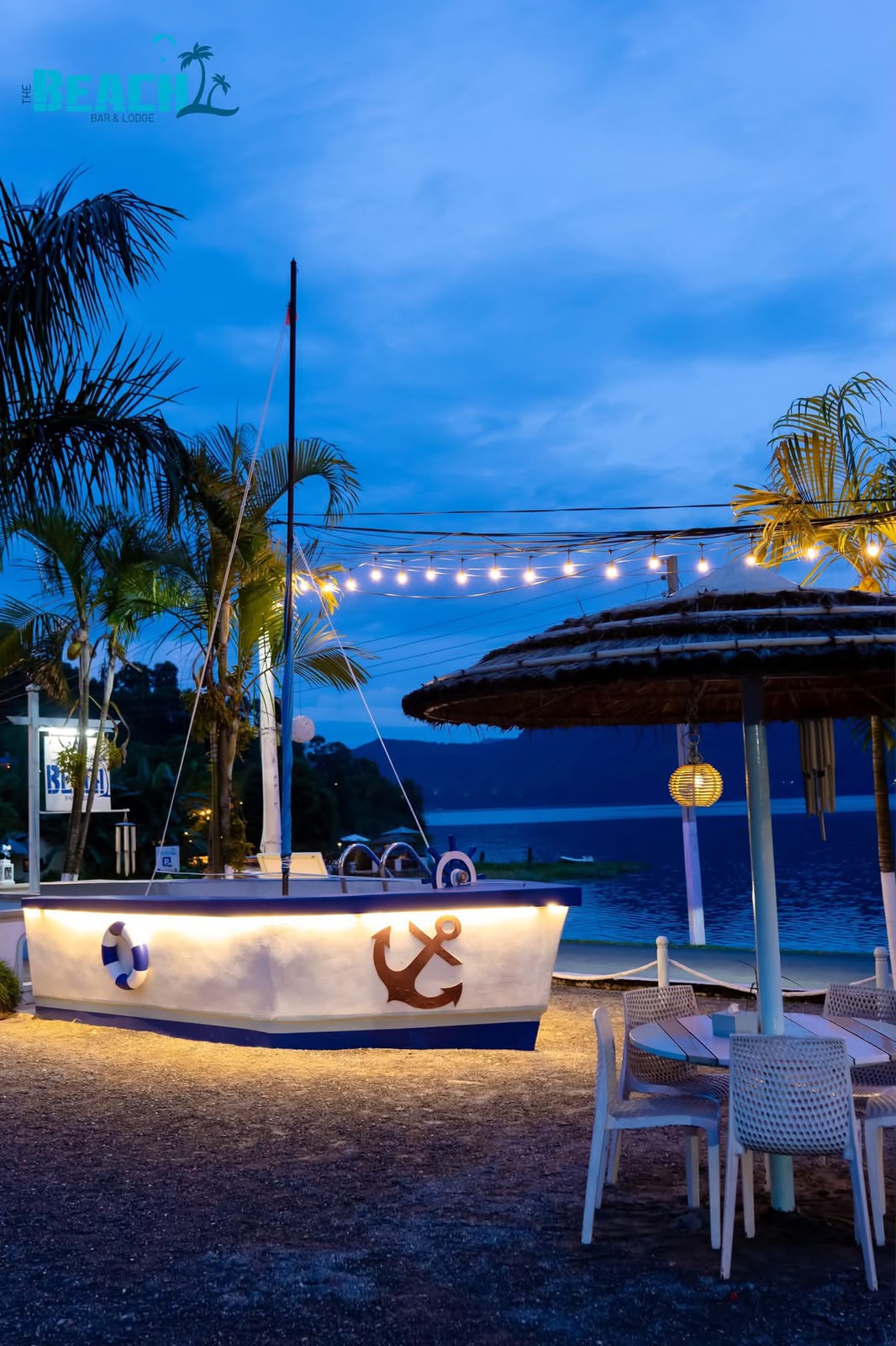 Tables and palms beneath terrace lights at blue hour